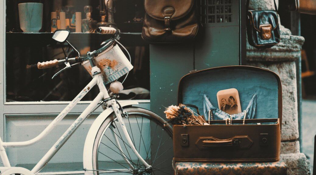 Vintage items such as bike and old suitcase on display in front of a shop